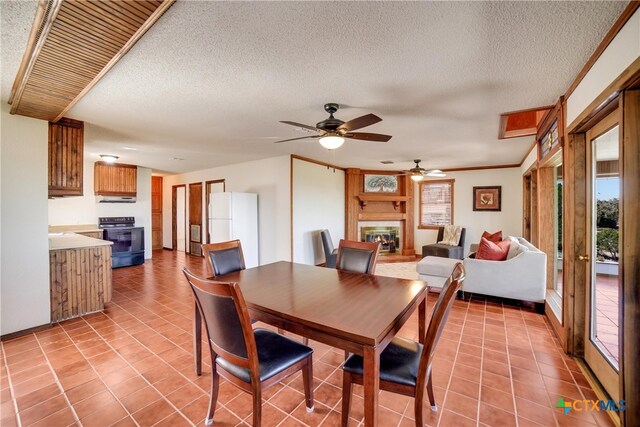 tiled dining room featuring ceiling fan, ornamental molding, and a textured ceiling