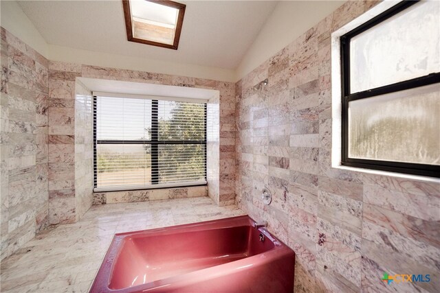 bathroom featuring a tub, tile walls, and vaulted ceiling