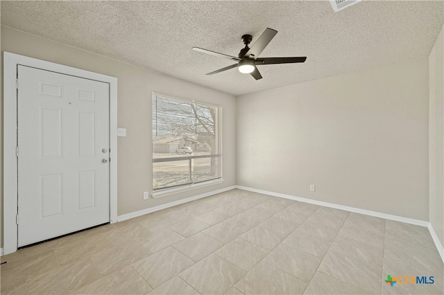 unfurnished room with a textured ceiling, visible vents, a ceiling fan, and baseboards