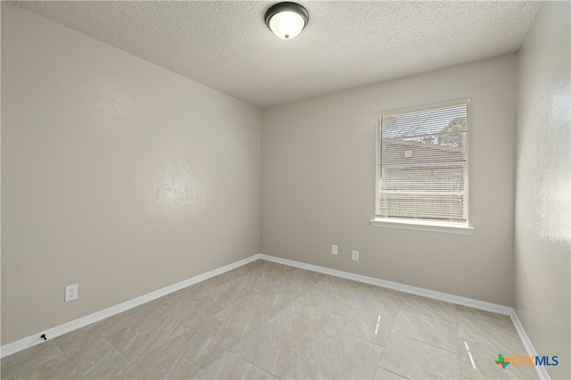 unfurnished room featuring light tile patterned flooring, a textured ceiling, and baseboards