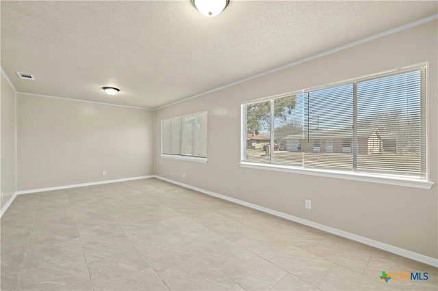 empty room featuring baseboards, a textured ceiling, visible vents, and crown molding