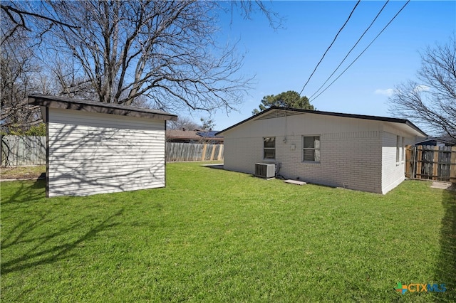 view of yard with a fenced backyard, central AC unit, and an outbuilding