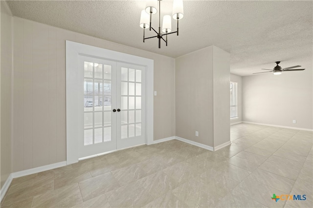 empty room with baseboards, ceiling fan with notable chandelier, a textured ceiling, and french doors