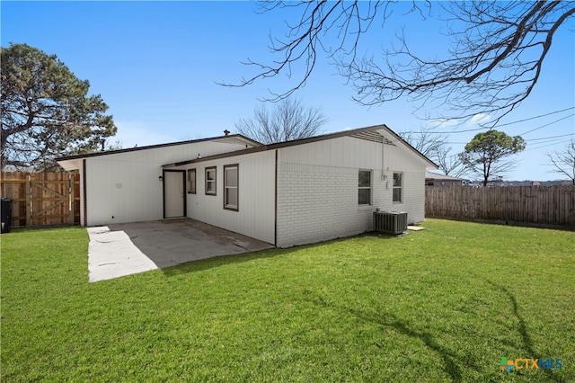 rear view of house with a lawn, a fenced backyard, central air condition unit, a patio area, and brick siding