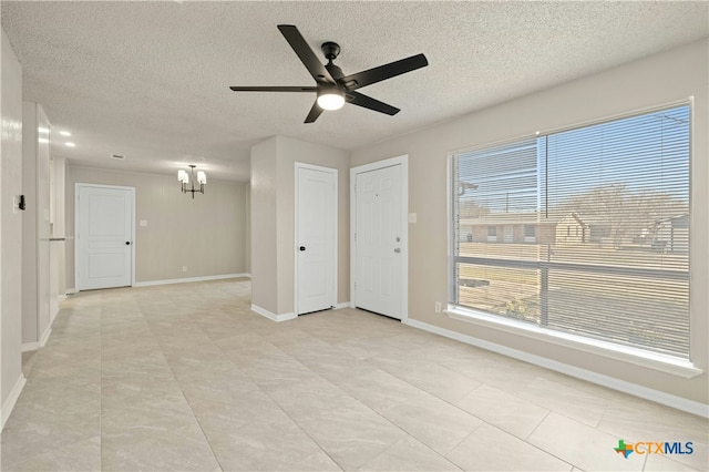 empty room with baseboards, a textured ceiling, and ceiling fan with notable chandelier