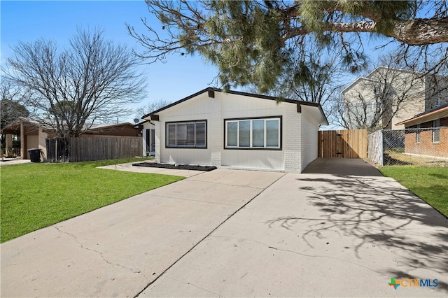 view of front of house with brick siding, fence, driveway, a gate, and a front yard