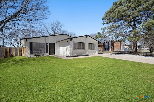 view of front facade with fence, a front lawn, and brick siding