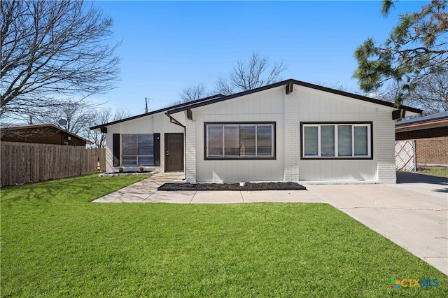 rear view of property with driveway, fence, a lawn, and brick siding