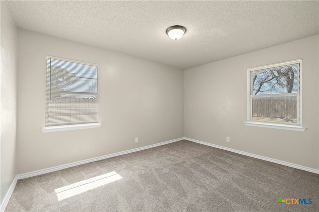 spare room featuring a textured ceiling, carpet floors, and baseboards