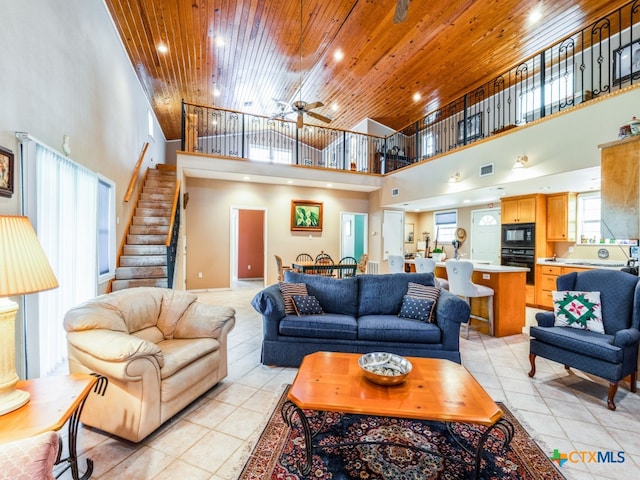 living room featuring a high ceiling, wooden ceiling, ceiling fan, and light tile patterned floors