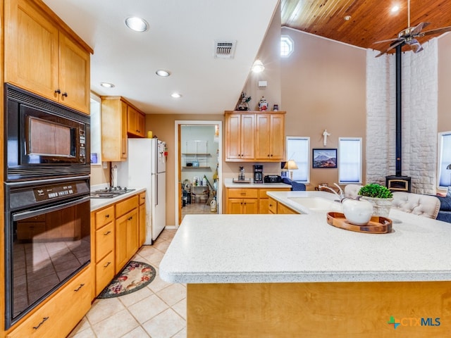 kitchen featuring a wood stove, black appliances, sink, wooden ceiling, and a kitchen island with sink