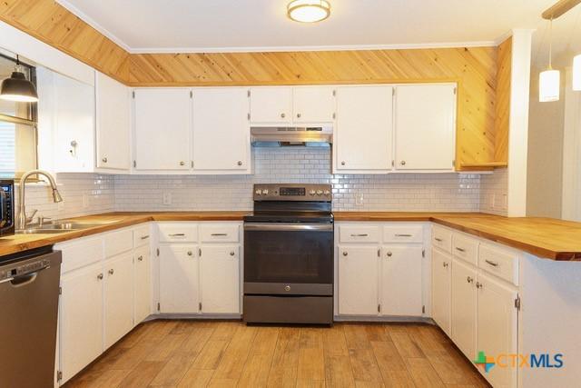 kitchen with stainless steel appliances, under cabinet range hood, a sink, decorative backsplash, and crown molding