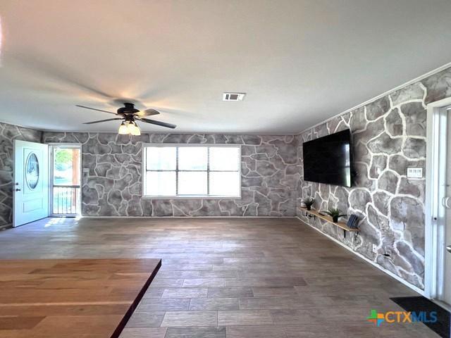 unfurnished living room with a ceiling fan and wood finished floors