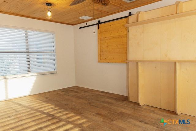 spare room featuring a barn door, wood ceiling, and light wood-style flooring