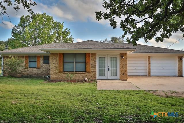 ranch-style house with french doors, a front lawn, concrete driveway, and brick siding