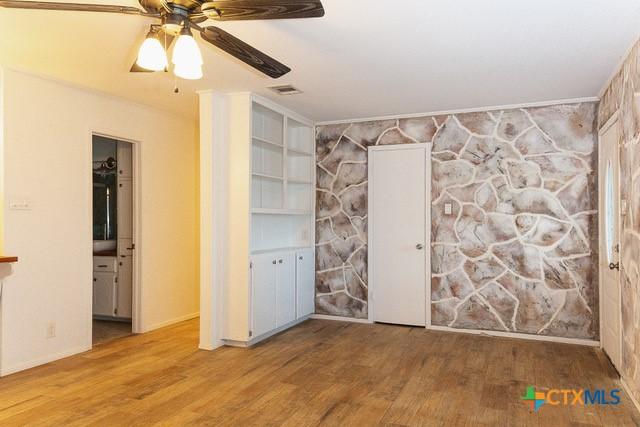 spare room with wood finished floors, a ceiling fan, and baseboards