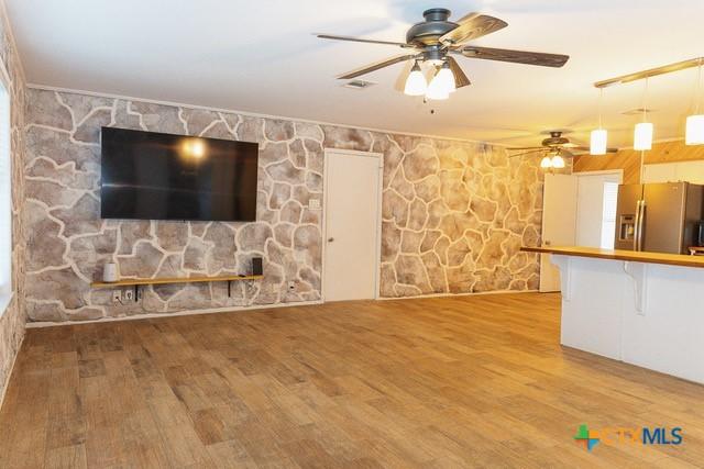 unfurnished living room with ceiling fan and wood finished floors