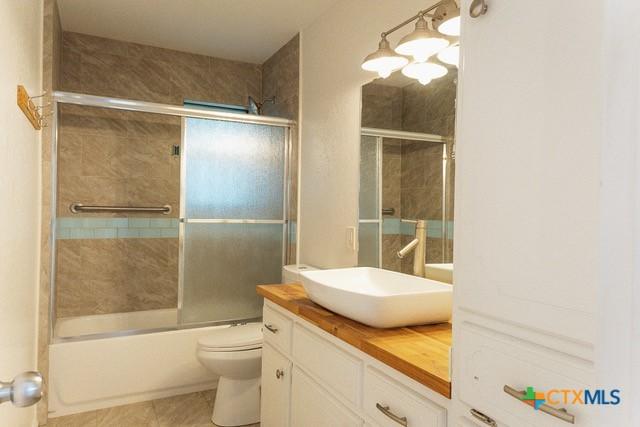 full bath featuring vanity, toilet, tile patterned flooring, and bath / shower combo with glass door
