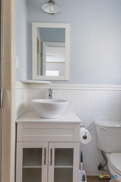 bathroom with wainscoting, toilet, and vanity