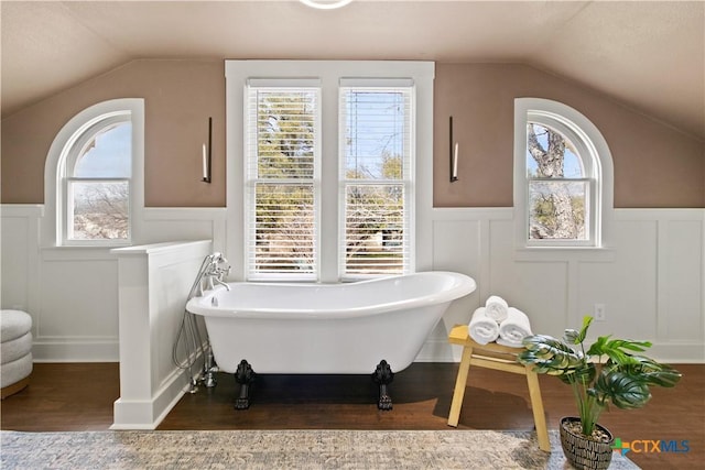 full bathroom featuring a healthy amount of sunlight, vaulted ceiling, and wood finished floors