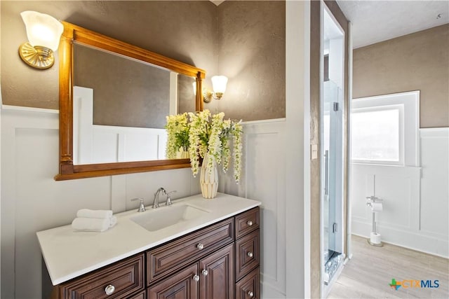 bathroom with a decorative wall, wood finished floors, and vanity