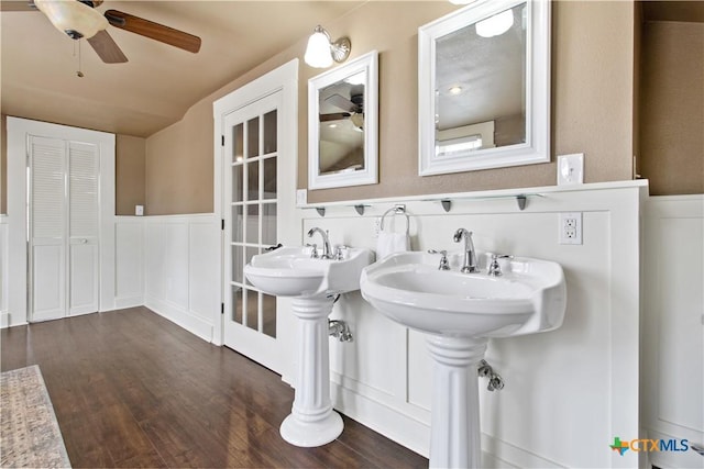 bathroom featuring a ceiling fan, a wainscoted wall, a decorative wall, and wood finished floors