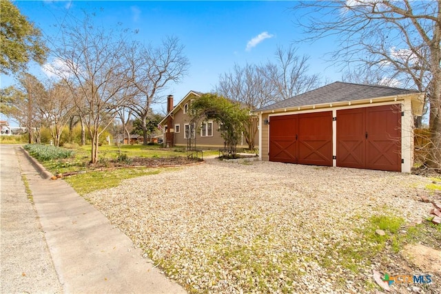 view of side of home with a shingled roof and an outbuilding