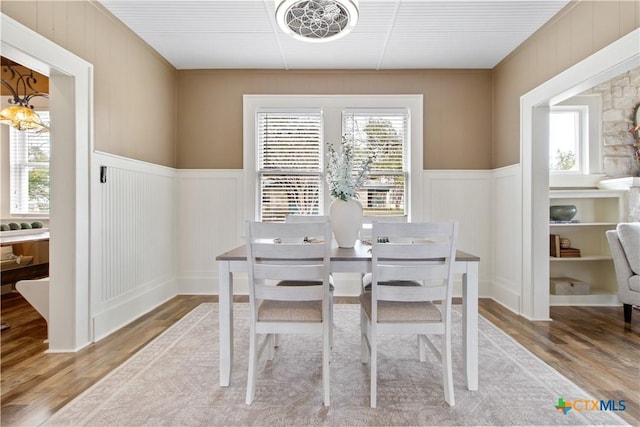 dining space featuring a wainscoted wall, a notable chandelier, and wood finished floors