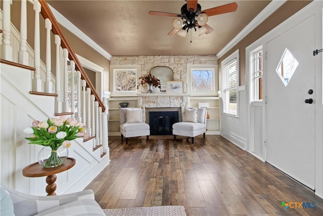 entryway featuring stairway, ornamental molding, a glass covered fireplace, a ceiling fan, and hardwood / wood-style floors