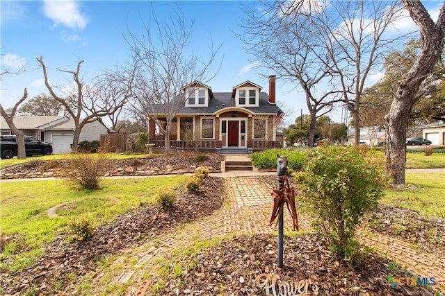 view of front of house featuring covered porch, a front lawn, and a chimney