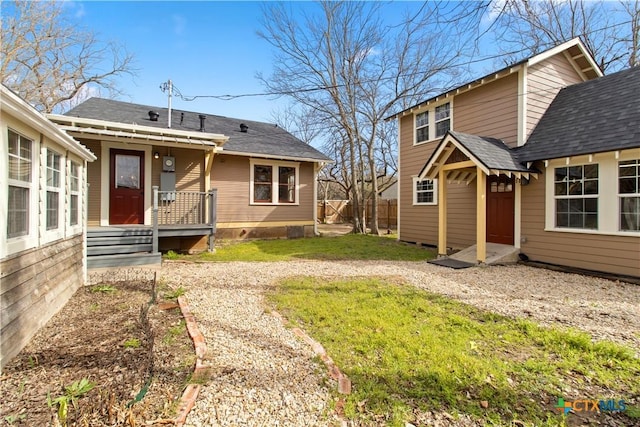 back of house with a yard, fence, and roof with shingles