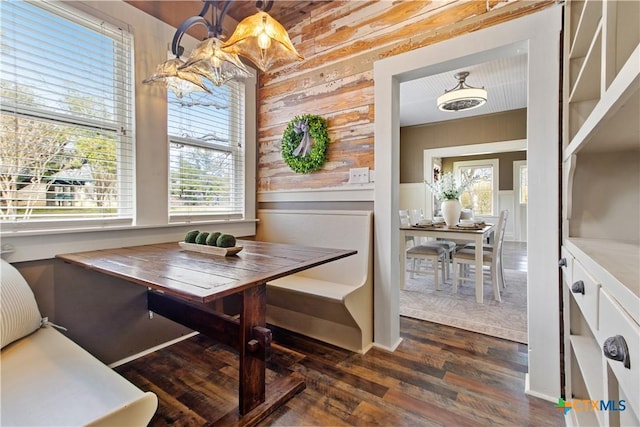 dining area featuring a wainscoted wall, dark wood-style flooring, and breakfast area