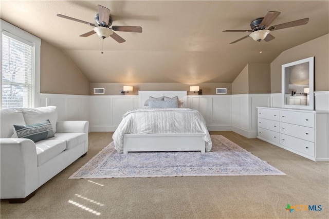 bedroom featuring a wainscoted wall, lofted ceiling, visible vents, and light colored carpet