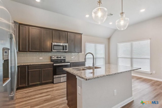 1202 Amber Dawn Dr, Temple, TX 76502 - kitchen with appliances with stainless steel finishes, tasteful backsplash, light wood-style floors, dark brown cabinetry, and vaulted ceiling