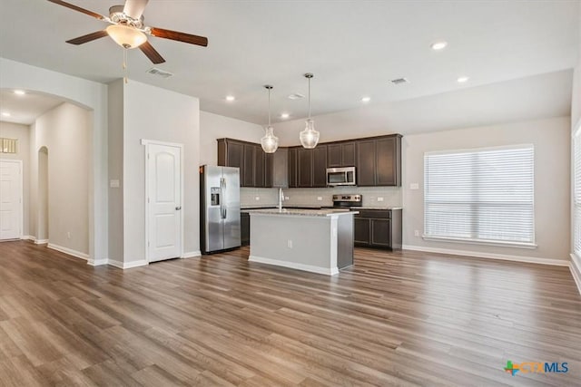 1202 Amber Dawn Dr, Temple, TX 76502 - kitchen with appliances with stainless steel finishes, open floor plan, arched walkways, dark brown cabinetry, and light countertops