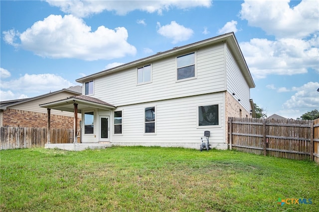 rear view of property featuring a lawn