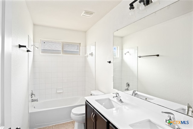 full bathroom featuring toilet, tiled shower / bath combo, vanity, and tile patterned flooring