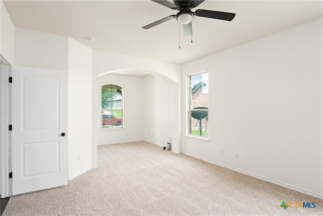 empty room with ceiling fan, a healthy amount of sunlight, and light carpet