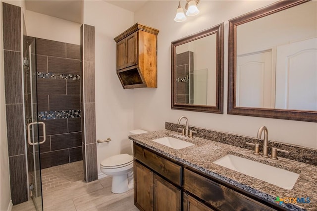 bathroom with double vanity, toilet, a shower stall, and a sink