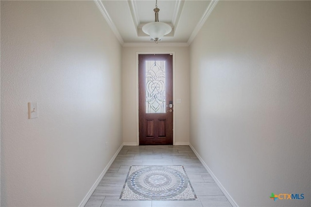 doorway with baseboards, ornamental molding, and a tray ceiling