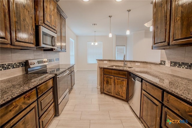 kitchen featuring dark stone counters, stainless steel appliances, backsplash, a sink, and visible vents