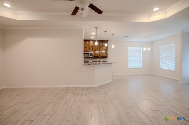 unfurnished living room featuring recessed lighting, ceiling fan, a tray ceiling, crown molding, and baseboards