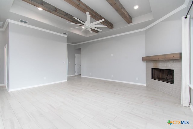 2904 Torino Reale Ave, Temple, TX 76502 - unfurnished living room with ceiling fan, beam ceiling, a tiled fireplace, light wood-style floors, and baseboards
