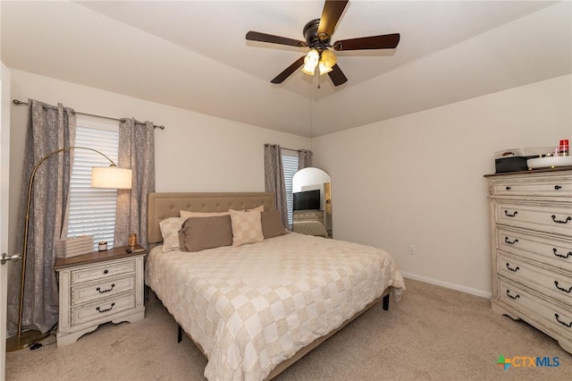 carpeted bedroom with ceiling fan and a tray ceiling