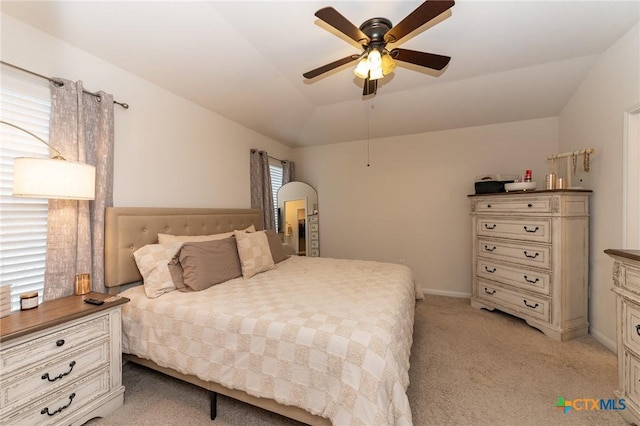 carpeted bedroom featuring lofted ceiling, a raised ceiling, and ceiling fan