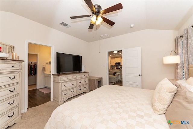 bedroom with lofted ceiling, a walk in closet, light colored carpet, a closet, and ceiling fan