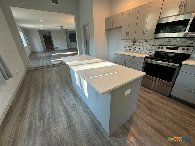 kitchen with appliances with stainless steel finishes, gray cabinetry, and dark hardwood / wood-style flooring