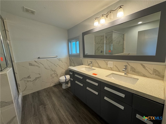 bathroom featuring toilet, tile walls, a textured ceiling, hardwood / wood-style flooring, and walk in shower