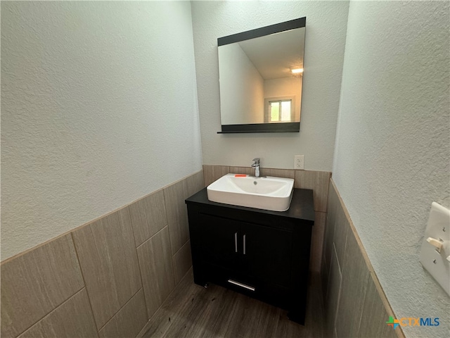 bathroom featuring hardwood / wood-style flooring, vanity, and tile walls