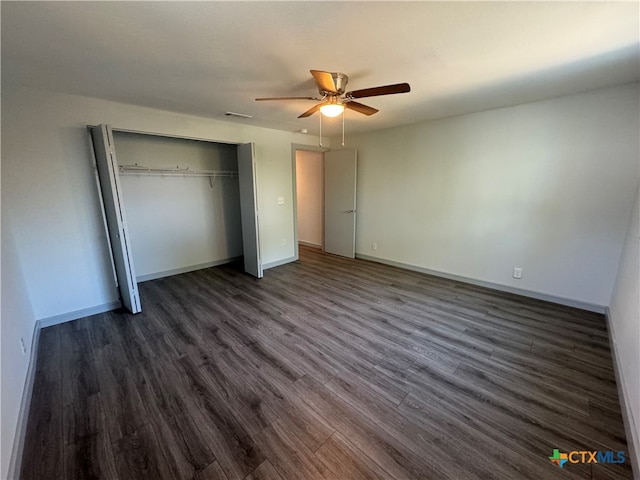 unfurnished bedroom featuring dark wood-type flooring, ceiling fan, and a closet